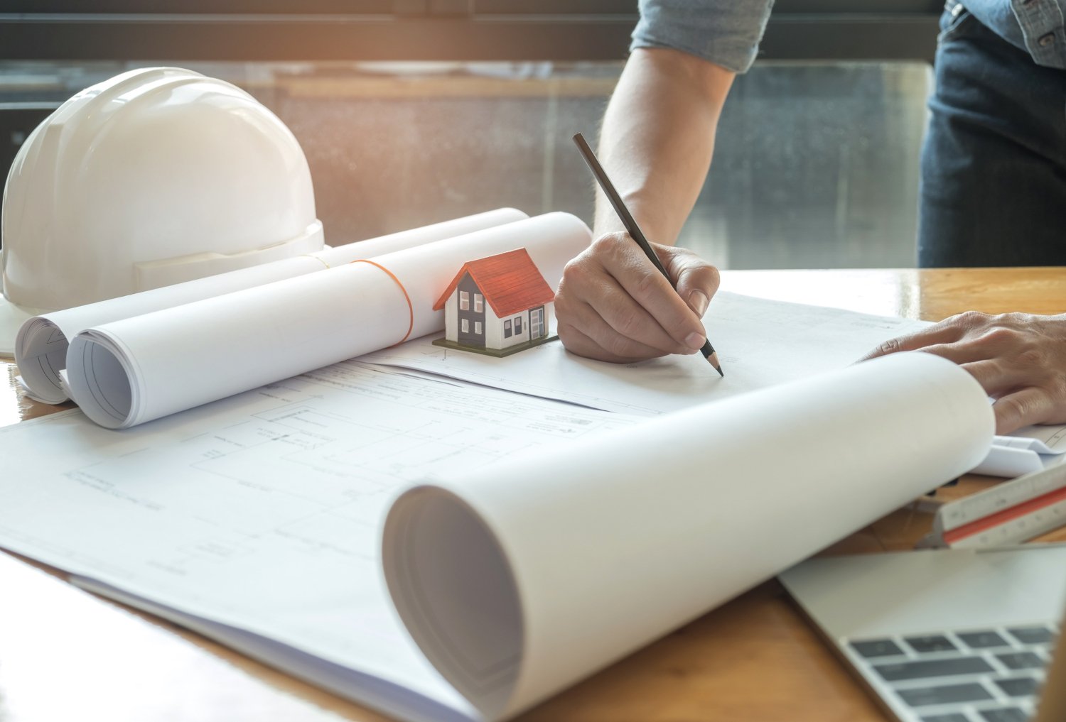 Les architectes écrivent avec le modèle de maison sur un bureau avec une maisonnette et un casque sur le côté